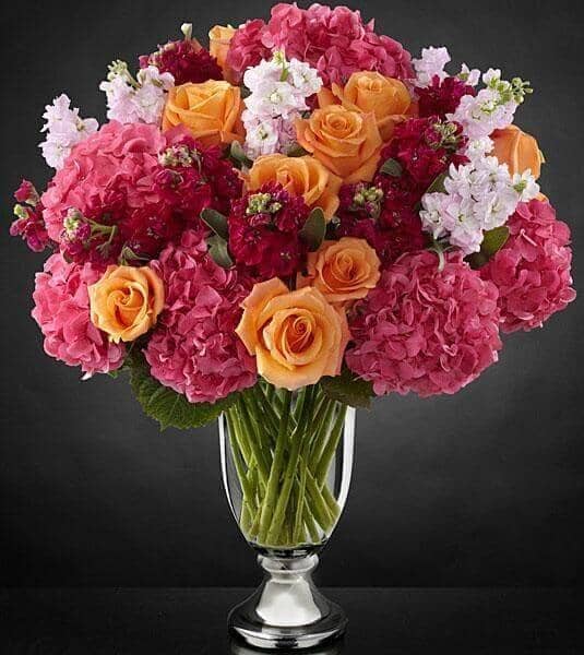 Astonishing™ Luxury Mixed Bouquet - 9 stems of orange roses, 6 stems of pink hydrangea, 10 stems of hot pink stock, 6 stems of pale pink stock and a Vera Wang glass and metal urn.