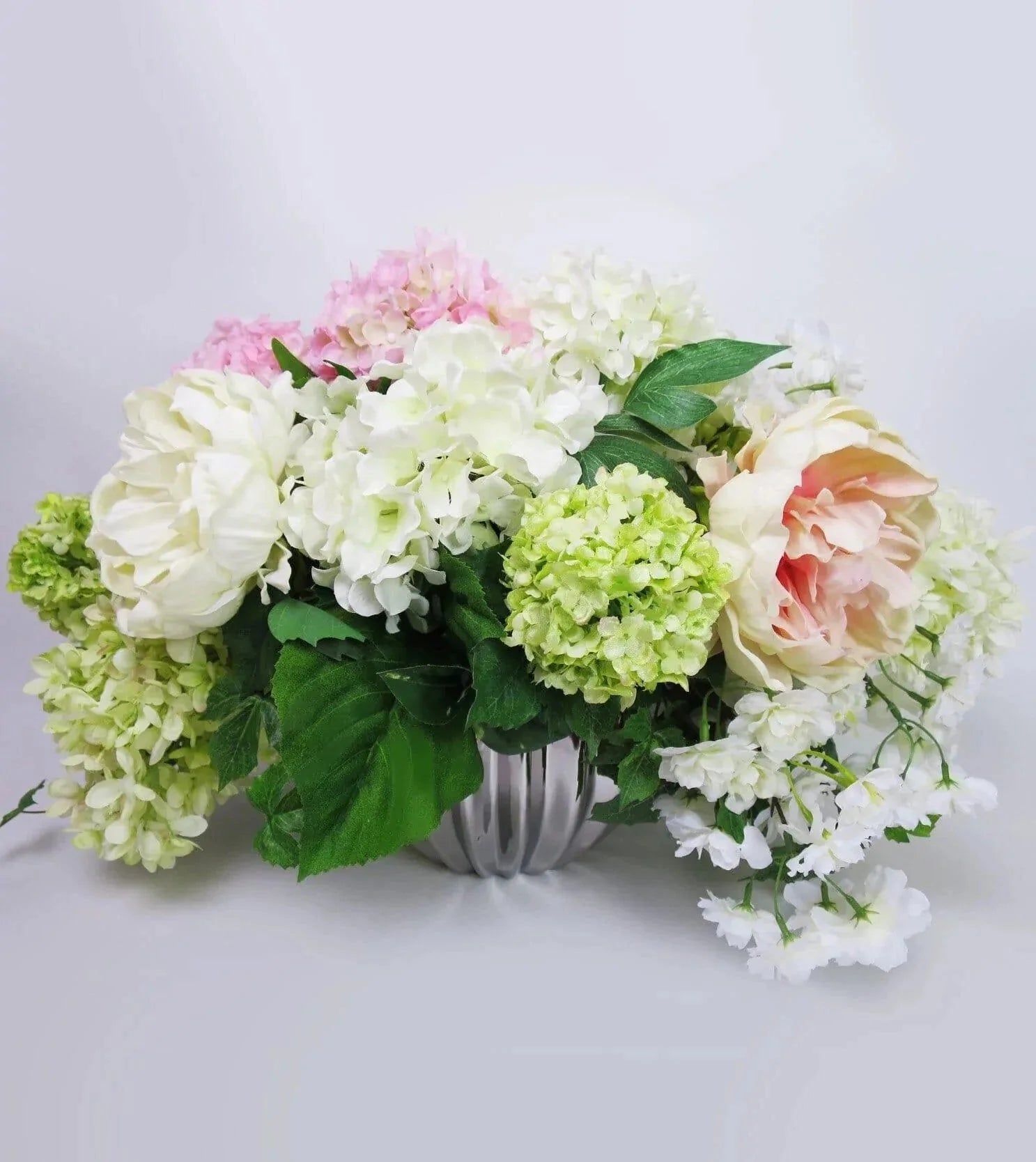 Pastel Silks - Pastel Silks - made with peach and white peonies, green, white, and pink hydrangeas, white cherry blossoms and lush greens come presented in an attractive modern silver container