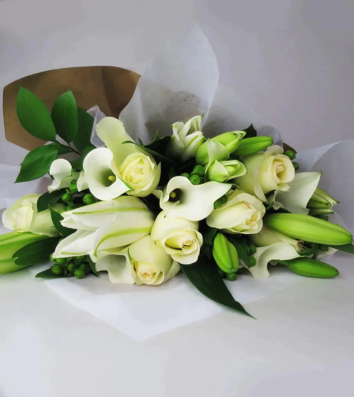 Sincere Wishes Bouquet™ - bouquet withWhite roses, white Mini Calla and Asiatic Lilies are arranged with Green Hypericum and Ruscus