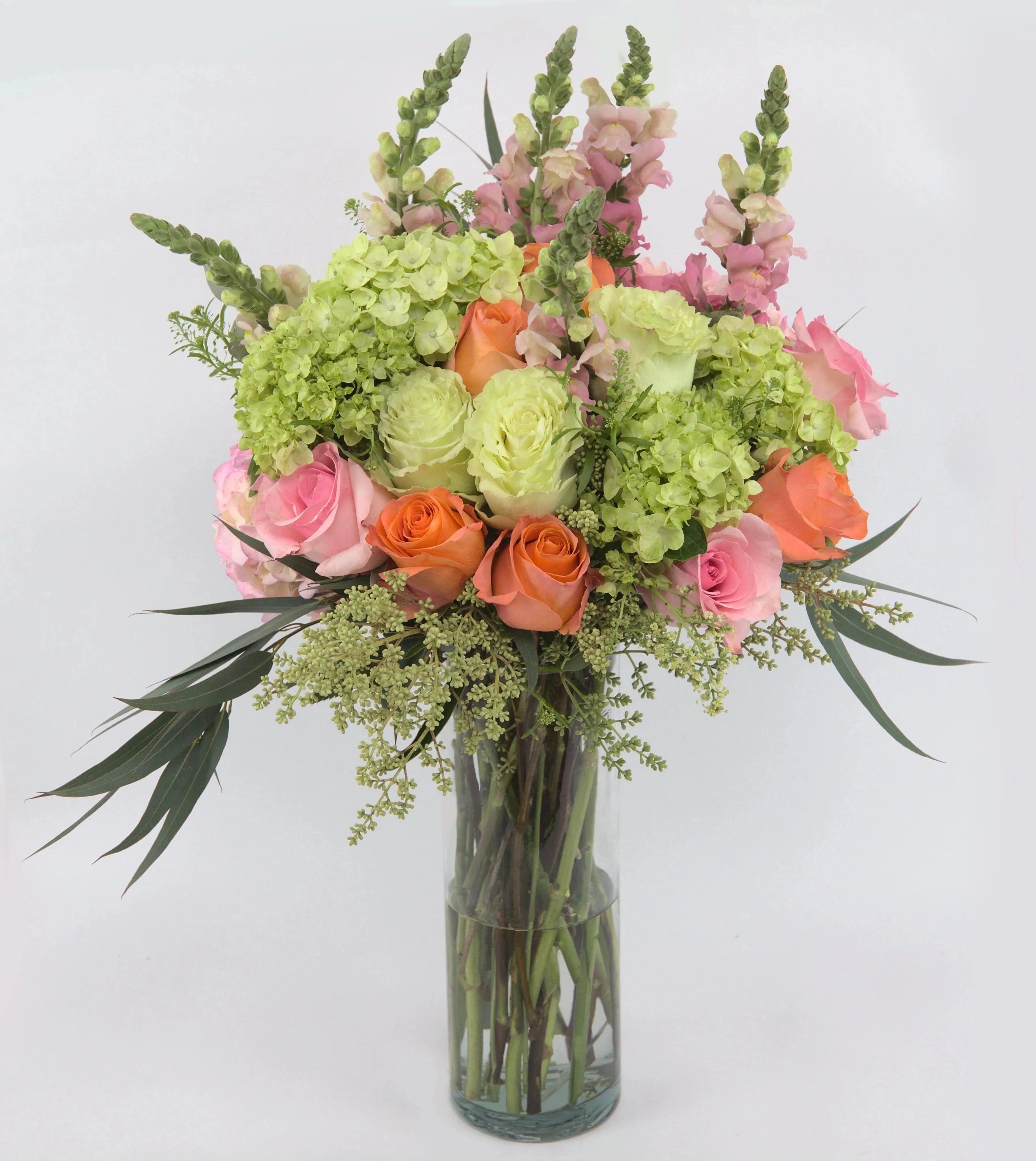Irreplaceable™ Luxury Bouquet - Vase of pink, peach, and green roses, with green and pink hydrangea blooms, snapdragons, bupleurum, seeded eucalyptus, and lush greens