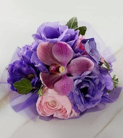 Purple Dusk™ Corsage - pink ranunculus , purple lisianthus , purple mokara orchids , purple hydrangea , delphinium , ivy vines , purple ribbon , corsage , wedding , prom , graduation